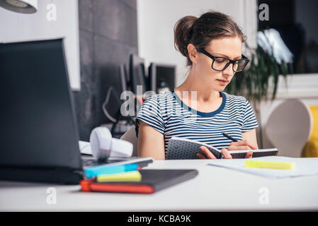 Woman wearing eyeglasses travailler tard au bureau et à l'écriture Banque D'Images