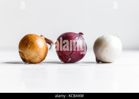 Trois ampoules sur un fond en bois blanc, oignons blancs., les oignons et les oignons rouges. Banque D'Images