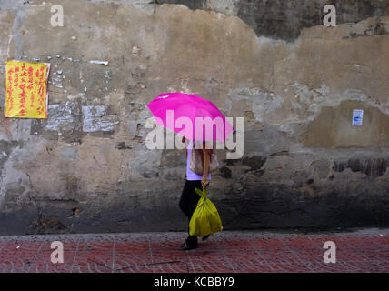 Une femme avec un parapluie rose marche dans une ruelle dans le quartier chinois, Bangkok, Thaïlande Banque D'Images