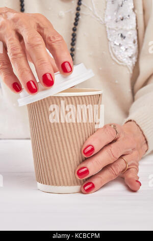 Femme de mains est une tasse à café en carton d'ouverture. Banque D'Images