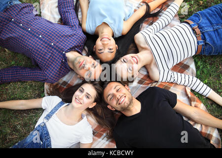 Cinq woman lying on grass top view portrait. heureux les jeunes femmes et les hommes dans les tenues de s'amuser à l'extérieur. des modèles masculins et féminins lookin Banque D'Images