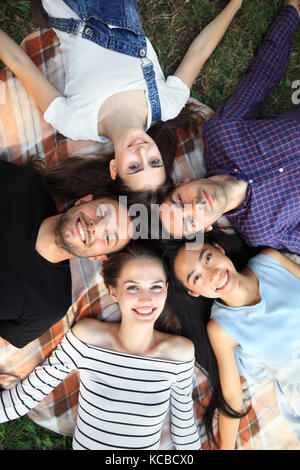 Cinq woman lying on grass top view portrait. heureux les jeunes femmes et les hommes dans les tenues de s'amuser à l'extérieur. des modèles masculins et féminins lookin Banque D'Images