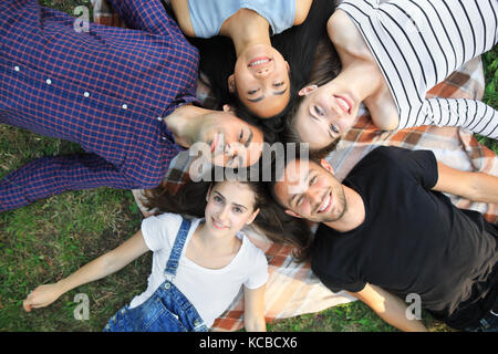 Cinq woman lying on grass top view portrait. heureux les jeunes femmes et les hommes dans les tenues de s'amuser à l'extérieur. des modèles masculins et féminins lookin Banque D'Images