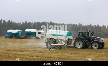 Tarvasjoki, Finlande - le 30 septembre 2017 tracteur Valtra étend : nordkalk la chaux agricole sur champ de chaumes en un jour brumeux de l'automne, avec agrilime Banque D'Images