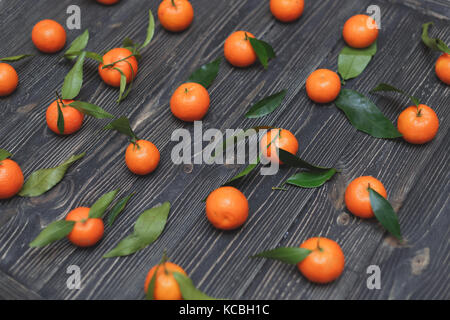 La nouvelle récolte de tangerines couché dans une lignes sur fond de texture en bois foncé Banque D'Images