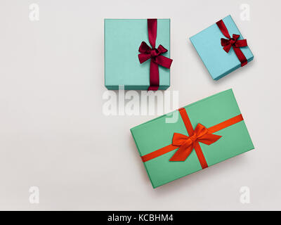 Boîte-cadeau photo tendance trois boîtes-cadeaux multicolores stylées Avec des rubans lumineux sur fond blanc vue du dessus photo moderne modèle avec espace f Banque D'Images
