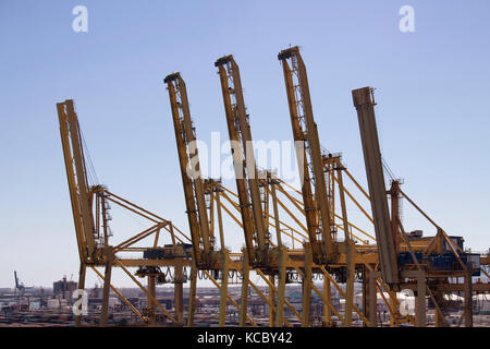 Vue rapprochée de grandes grues géantes, au port de Barcelone. De nombreux conteneurs sont en arrière-plan. Banque D'Images