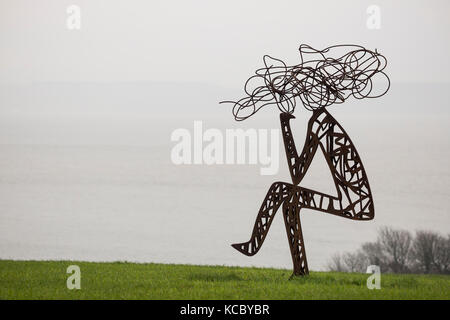 Metal Sculpture en plein air de l'homme assis stylisé dans le champ Banque D'Images