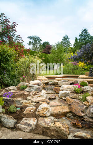 Un jardin de rocaille nouvellement plantées après l'installation d'une main-construit en pierre naturelle cascade dans un jardin anglais en UK Banque D'Images