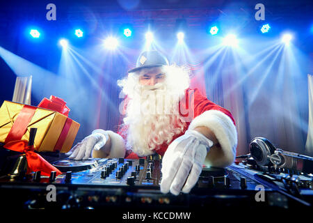 Funny santa mix dj dans les faisceaux de lumière de la musique. Banque D'Images