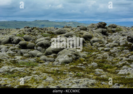 De pierres de lave couvertes de mousse avec ciel bleu et les montagnes en arrière-plan, en Islande Banque D'Images