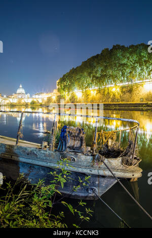 Belle vue de la nuit de la Basilique Saint Pierre. Photo prise sur les rives du Tibre, avec un vieux bateau en premier plan Banque D'Images