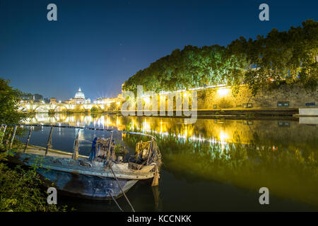 Belle vue de la nuit de la Basilique Saint Pierre. Photo prise sur les rives du Tibre, avec un vieux bateau en premier plan Banque D'Images