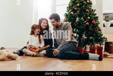 Assis à côté de la famille de l'ouverture de l'arbre de Noël des cadeaux. Petite famille heureuse d'avoir du temps ensemble de Noël. Banque D'Images