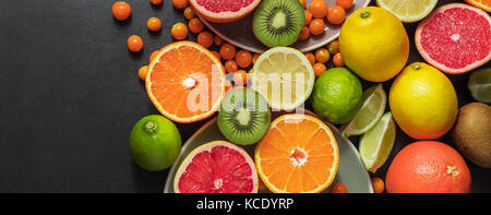 Variété de fruits dans les assiettes de service et sur la table. Les oranges, pamplemousse, citron vert, kiwi et fruits de mer regroupé sur une table. Banque D'Images