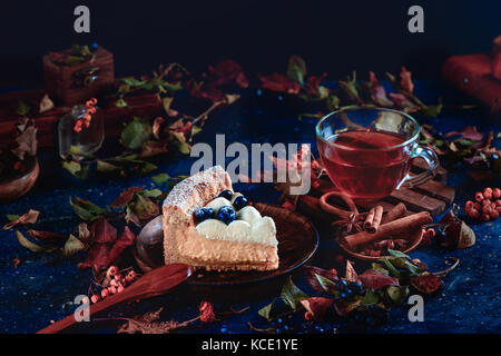 Hommemade wipped croûte gâteau à la crème, les bleuets et purée de potiron sur un fond noir avec verre d'eau, les feuilles d'automne et la cannelle. close-up d'un morceau de gâteau. the food. Banque D'Images