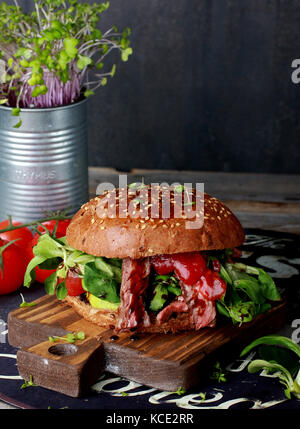 Big burger de viande juteuse sur planche de bois Banque D'Images