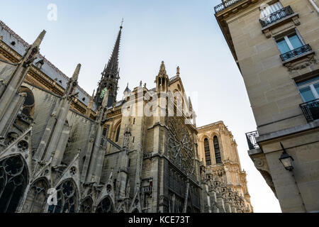 Low angle view of the North Face et flèche de la cathédrale Notre-Dame de Paris au coucher du soleil avec un bâtiment résidentiel dans l'avant-plan. Banque D'Images