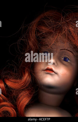 Extreme close-up of red-haired poupées en biscuit, yeux bleus, tête lèvres rouge. attrayant, énigmatiques. Couverture de livre, portrait Banque D'Images