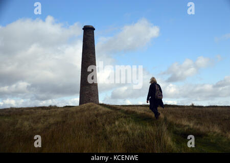 Randonneur femme marche et la cheminée de l'usine d'éperlans à Grassington's Old mines désaffectées sur Malham Moor, Wharfedale, Yorkshire Dales National Park, Banque D'Images