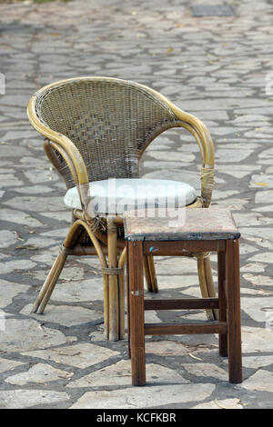 Une chaise en osier et d'un tabouret ou une table à l'extérieur sur la rue à kerkira, Corfou, Grèce. Banque D'Images