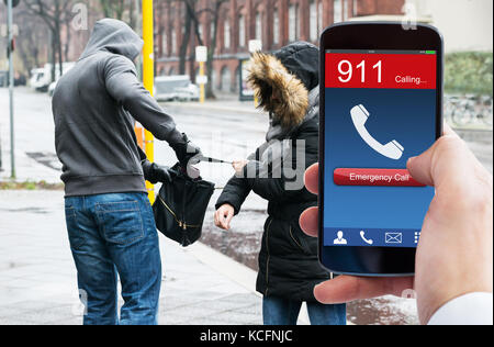 La main de personne composant appel d'urgence sur téléphone mobile alors que le vol de sac à main de femme antivol Banque D'Images