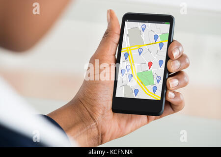 Close up of woman's hand holding mobile phone avec divers marque l'emplacement sur la carte Banque D'Images