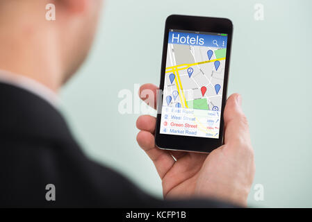 Close-up d'une personne recherchant les hôtels utilisant la carte GPS de navigation avec des pointeurs sur son smartphone Banque D'Images