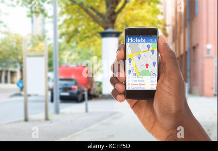 Close-up d'une personne à l'aide de téléphone mobile pour rechercher des Hotels Banque D'Images