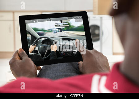 Close-up of Man Using Digital Tablet vient jouer Jeu Voiture Banque D'Images