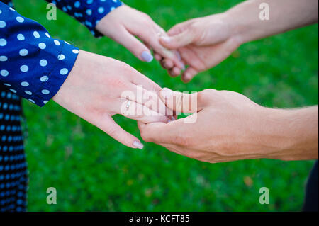 Deux paires de mains dans l'amour tendrement tenir ensemble sur fond d'herbe verte Banque D'Images