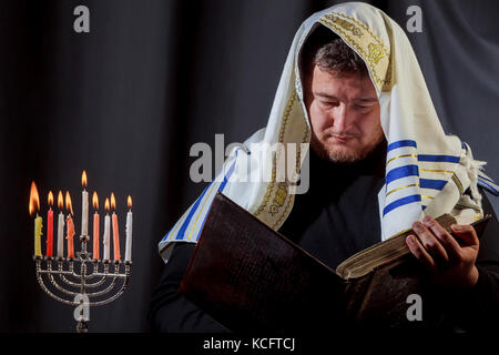 L'homme juif avec les bougies d'éclairage barbe homme juif dans la prière d'une menorah lumière des bougies sur un Juif Hanukkah Banque D'Images