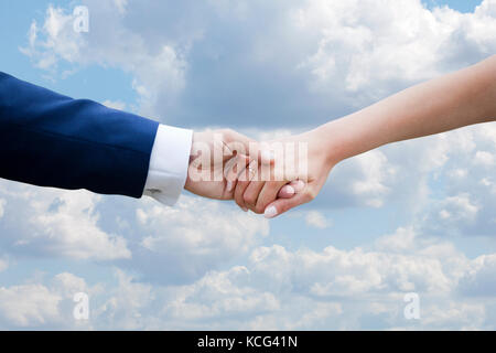 Wedding couple holding hands on blue sky with clouds Banque D'Images