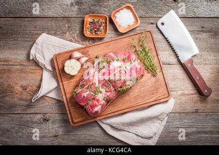 Matières roastbeef viande coupée avec l'hyme et l'ail et le couteau sur une planche à découper de vieux fond de bois, vue du dessus Banque D'Images