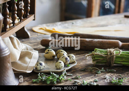 Ingrédients pour faire des pâtes, rouleau à pâtisserie, œufs de caille, les asperges sur table en bois Banque D'Images