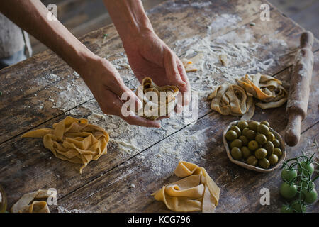 Le jeune homme dans le tablier faisant des pâtes maison Banque D'Images