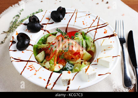 Salade grecque dans le livre blanc de profondeur plaque avec la fourchette et couteau Banque D'Images