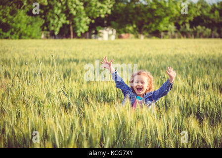 Happy girl avec mains playing in wheat field Banque D'Images