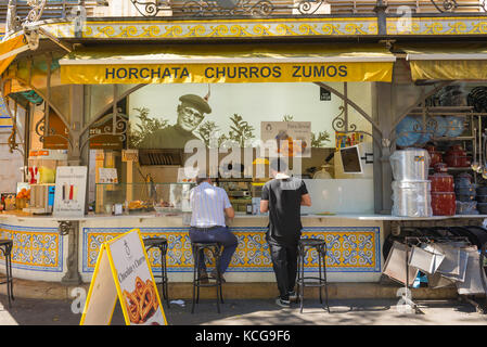 Espagne cuisine de rue, vue de deux hommes en utilisant un kiosque de nourriture de rue spécialisé dans les churros et horchata dans le quartier de la vieille ville de Valence, Espagne. Banque D'Images