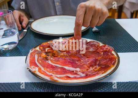 La main de l'homme avoir dans un restaurant CHORIZO IBÉRIQUE. Salamanque, Espagne. Banque D'Images