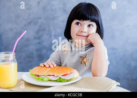 Peu de cheveux cute black girl eating sandwich à la maison Banque D'Images