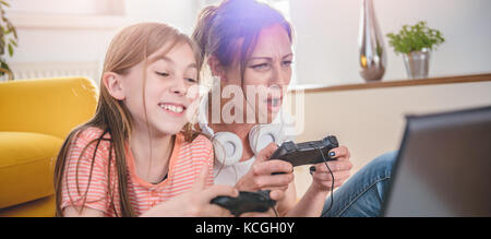 Mère et fille jouer à des jeux vidéo sur ordinateur portable à la maison Banque D'Images