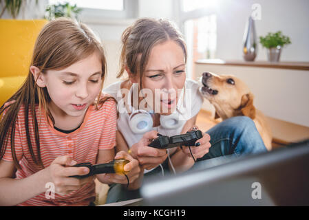 Mère et fille jouer à des jeux vidéo sur ordinateur portable à la maison Banque D'Images