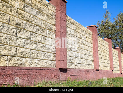 Clôture faite de briques et de plâtre décoratif. jaune clôture avec éléments rouge. haut et beau l'escrime. Banque D'Images