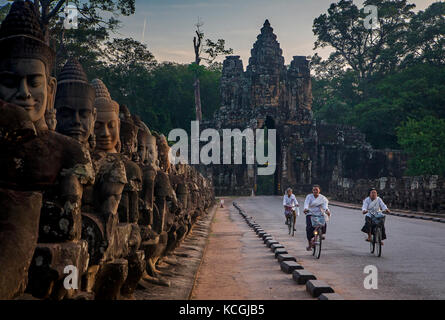 Femme, femme, vélo, Pont et porte sud d'Angkor Thom, Angkor, Siem Reap, Cambodge Banque D'Images