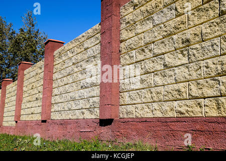 Clôture faite de briques et de plâtre décoratif. jaune clôture avec éléments rouge. haut et beau l'escrime. Banque D'Images