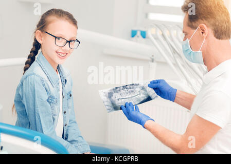 Smiling teen dame à la caméra en soins dentaires pendant checkup Banque D'Images