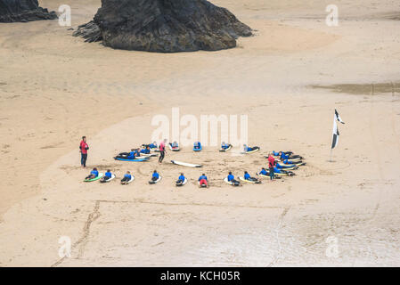 Le surf au Royaume-Uni. Les jeunes de l'écoute d'un instructeur de surf au début de leur leçon de surf à Newquay Cornwall. Banque D'Images