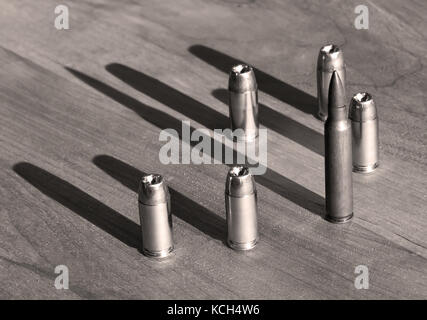 Cinq balles à pointe creuse de calibre 40 avec un 223 sur une ronde FMJ table en bois en noir et blanc Banque D'Images