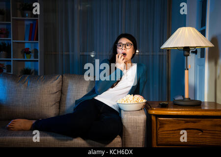 Élégante beauté girl watching film d'horreur dans la nuit à la parcelle au terrible crainte et choqué avec coin à manger salon canapé popcor Banque D'Images